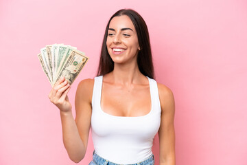 Young caucasian woman taking a lot of money isolated on pink background with happy expression