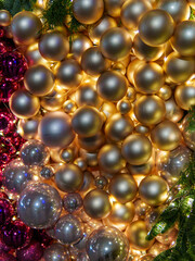 A festive arrangement of golden and purple ornaments is illuminated, creating a warm, inviting atmosphere for the holiday season. The shiny globes reflect light beautifully.