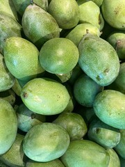 Closeup of mangoes, mango fruit, tropical fruit. Fresh green manggo for sale at traditional market. Selective focus. Piles of ripe mangoes on display for sale.