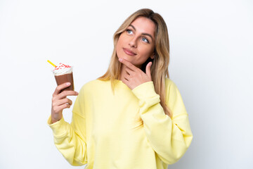 Young Uruguayan woman holding Frappuccino isolated on white background looking up while smiling