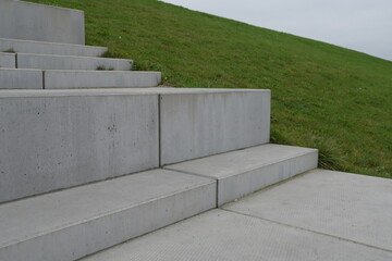 grauestufen aus beton zum sitzen an einer grünen wiese