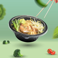 Picture of Pad Thai put in a black plastic cup.
placed in a green background and contains various vegetable ingredients
There are both red and green vegetables, very delicious to eat.