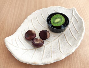 Kiwi and shiny brown chestnuts on the table