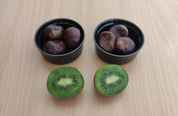 Kiwi and shiny brown chestnuts on the table