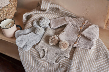 Fototapeta premium Knitted kids clothes, yarn and accessories for knitting. Needlework and knitting. Hobbies and creativity. Knit for children. Handmade. Christmas tree background