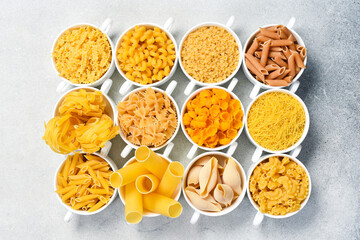 Different uncooked pasta on light stone table. Top view.