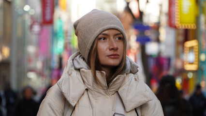 Pretty woman smiling in a knitted hat on a background of the city.