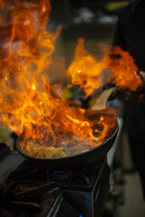 cooking steak in a restaurant kitchen with a fire in a pan