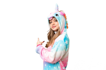 Young girl with unicorn pajamas over isolated chroma key background pointing back