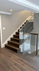 Obraz premium Modern staircase with wooden steps and glass railing in a well-lit interior space.