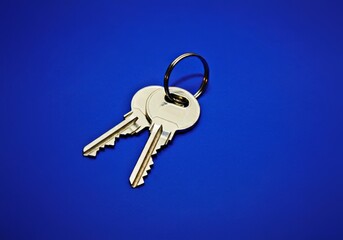 A shiny pair of keys on a vivid blue surface