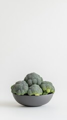 Fototapeta premium Fresh and vibrant broccoli displayed in a modern gray bowl against a minimalist white background for a stylish culinary presentation