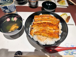 Delicious grilled eel on rice served with soup and pickled vegetables in a Japanese restaurant setting.