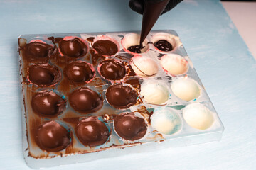 Confectioner's hands fill with chocolate, molds for making homemade chocolates using a cooking bag