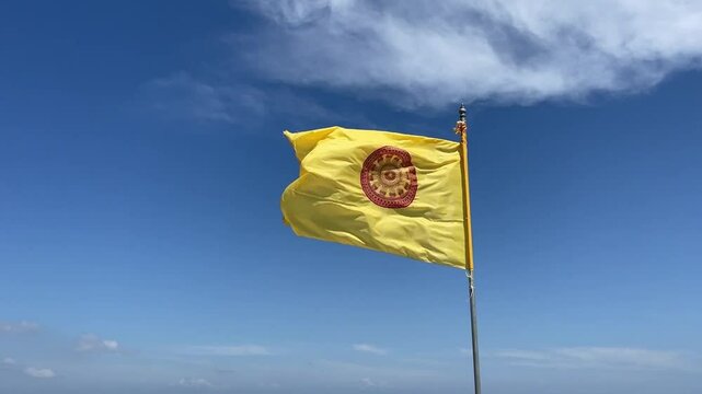 Thai Buddhist Flag in wind. Temples flies the yellow and red tong dhammachak - Thai Buddhist flag. The red circle is a dharma wheel (dhammachak in Thai) this represents dharma the teaching of Buddha