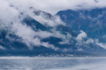 Obraz premium View from a tourist boat at the misty Kenai Mountains and the town of Seward in the distance, Kenai Peninsula, Alaska, USA 