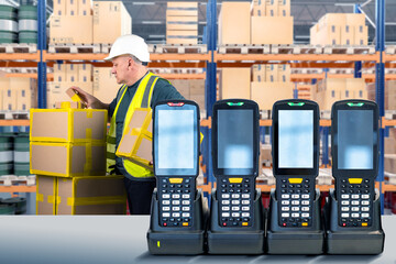 Warehouse equipment. Data collection terminals on table. Devices for recording goods in warehouse. Several laser scanners for barcodes. Man storekeeper behind data collection terminals
