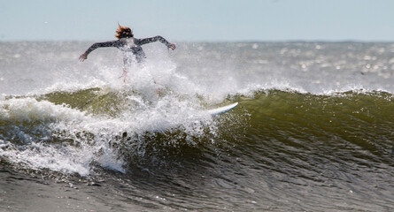 Surfer Showcases Skill While Riding a Powerful Wave on a Sunny Day at the Beach