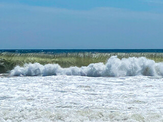 Waves Crashing on a Sandy Beach During a Sunny Day Near the Ocean