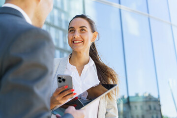 Professionals engaging in conversation outside modern office building during sunny day