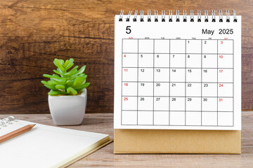 May 2025 desk calendar on table.