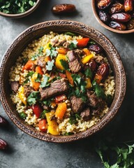 A bowl of couscous topped with beef, peppers, and herbs, showcasing a colorful meal.