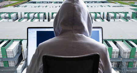 Close-up of a hacker behind a laptop and a large datacenter in the background