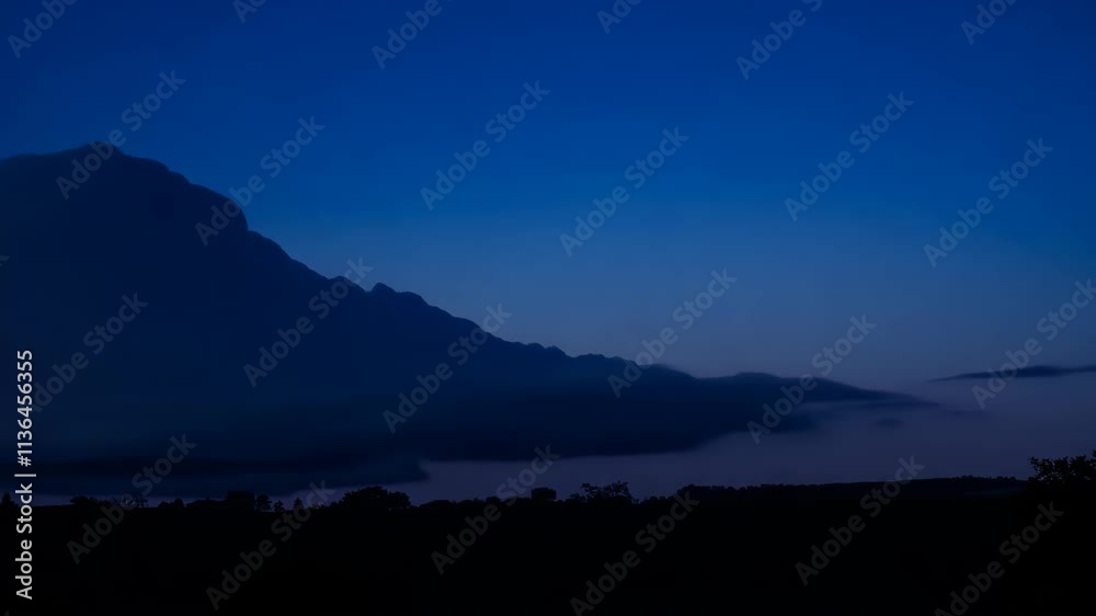 Poster Clouds passing over mountains at dusk creating a calming atmosphere in nature