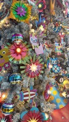 Obraz premium A silver Christmas tree adorned with vibrant ornaments, handcrafted flowers, festive hats, rockets, and toys like pink cats, robots, and yellow ducks. Perfect for holiday cards or banners.