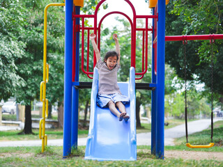 Cute girl playing in the playground during summer vacation. Happy girl having fun on a colorful...