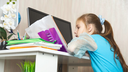 Little school girl sit at table at home write in exercise book prepare homework alone.