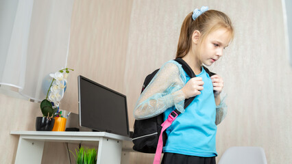 School girl putting on her backpack in room, as she gets ready to go to school