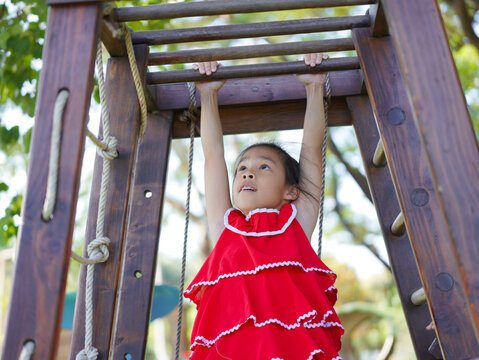 Cute girl playing in the playground during summer vacation. Happy children having fun in an outdoor park.