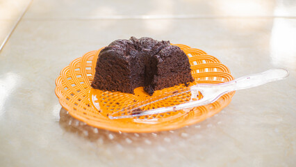 Delicious chocolate brownie cake that has been cut into pieces on an orange plate and clear cake knife