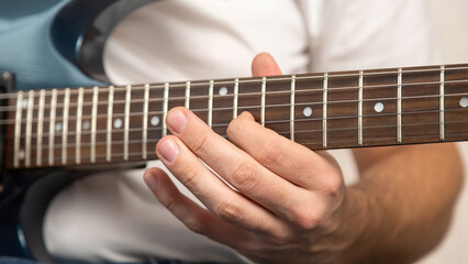 Obraz premium Guitar music. Practice chords. Male performer hands with fingers studying melody of song on electric string guitar fretboard indoors.