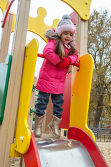 Little girl having fun on playground. Happy healthy little child climbing, swinging and sliding on...