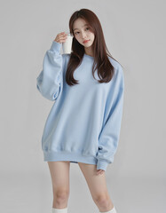 Full Body Photo of Asian Girl in Light Blue Loose Sweatshirt and White Short Skirt holding coffee cup Posing Against Simple Background	