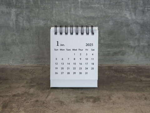 January 2025 page of desk calendar for organizer to plan and reminder, standing on grunge concrete table background, loft style. White small table calendar with the first month, Happy new year 2025.