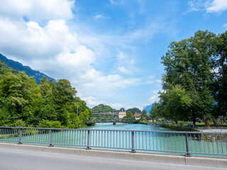 Bridge road over the Lake Brienz in the morning scene, fresh green water between the town and mountain with summer blue sky background, view from the bridge at Interlaken, Switzerland.