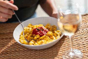 Young woman hands eating a plate of pasta in the kitchen at home