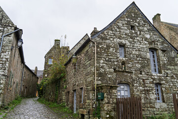 Une ruelle &eacute;troite de Locronan, bord&eacute;e de maisons en pierre. Les pav&eacute;s mouill&eacute;s refl&egrave;tent le ciel gris d'automne, donnant &agrave; la sc&egrave;ne une atmosph&egrave;re calme et intime.