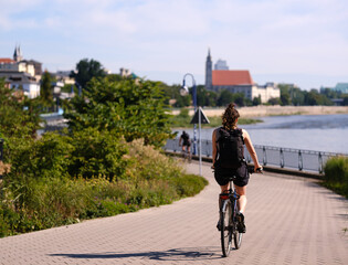 Radfahrer an der Elbe mit Kirche im Hintergrund bei Sonnenschein in Magdeburg