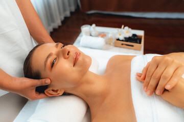 Caucasian woman enjoying relaxing anti-stress head massage and pampering facial beauty skin recreation leisure in dayspa modern light ambient at luxury resort or hotel spa salon. Quiescent