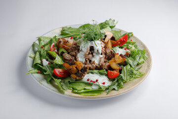 On a table, there is a plate filled with various vegetables and meat
