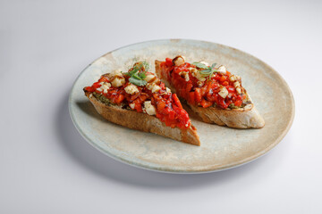There are two slices of bread topped with tomatoes and cheese on a plate