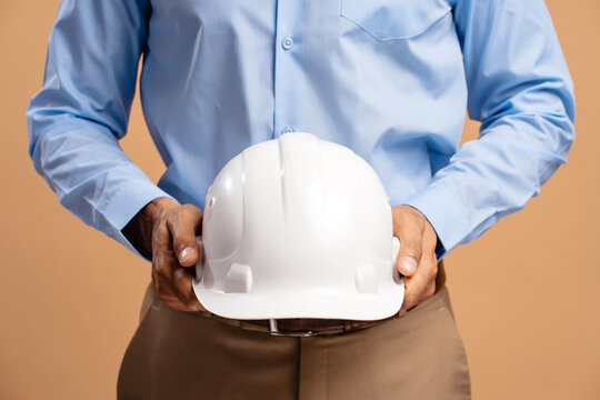 Closeup, successful engineer holding white hard hat, selective focus on hands