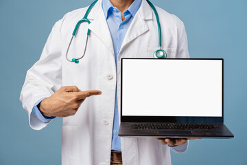 Doctor wearing white coat and stethoscope holding laptop pointing finger on white empty screen