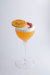 A cocktail in a wine glass, elegantly topped with a slice of orange