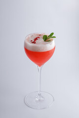 A red drink in a wine glass, topped with a fresh mint leaf