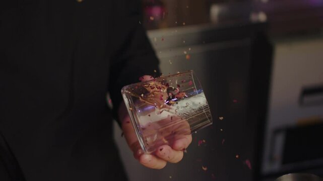 The bartender decorates the glass with freeze dried raspberries, berries fly off